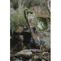 man in red t-shirt climbing a cliff face